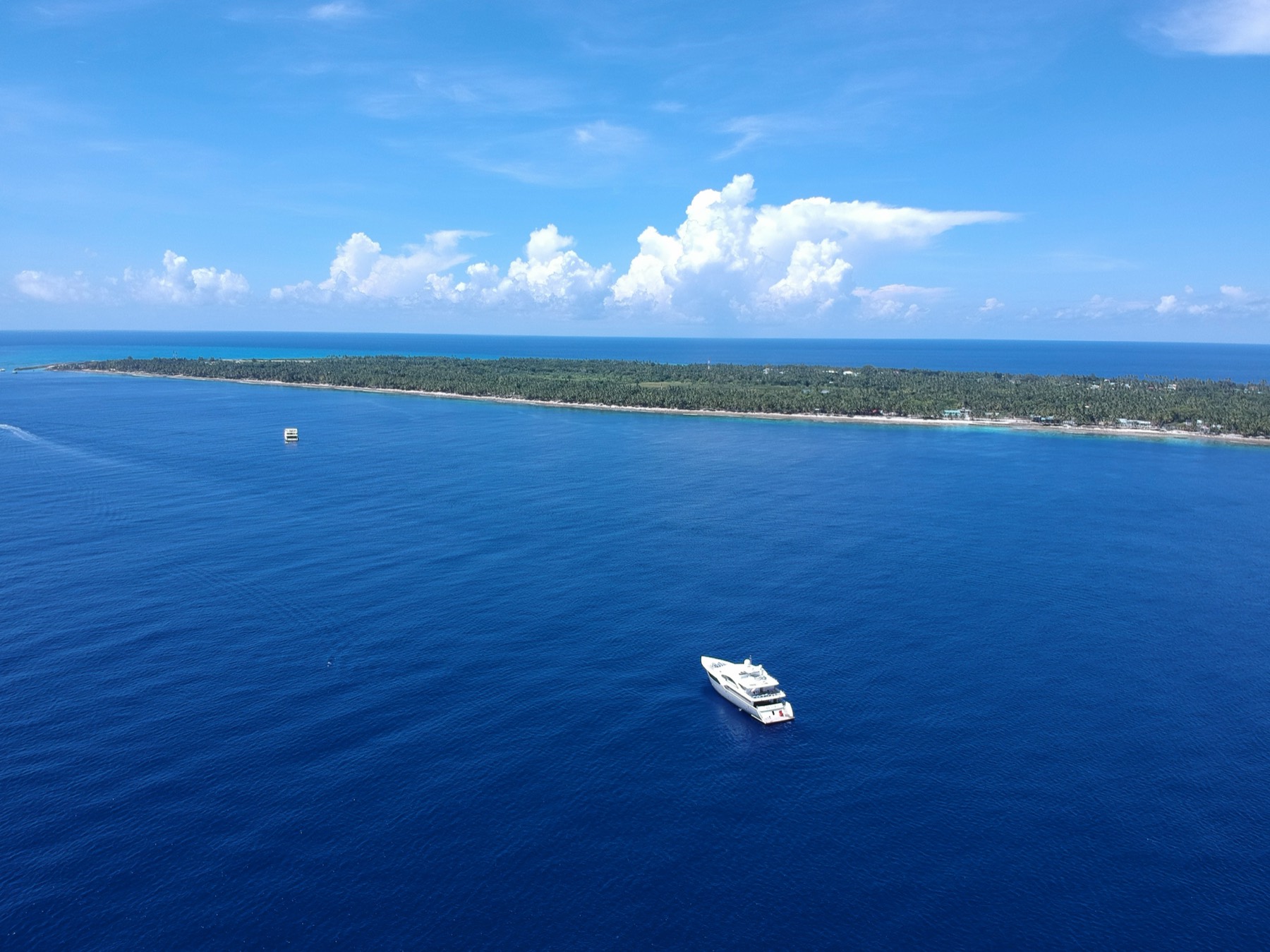Aerial view of Fuvahmulah's coast with dive boats anchored in deep blue water